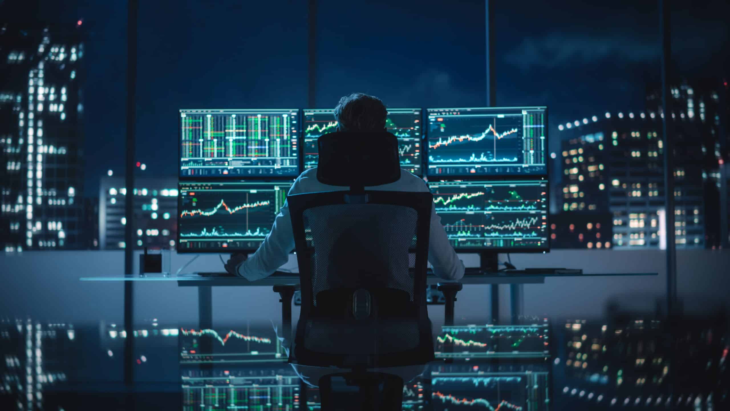 Stock photo of a financial analyst working on many screens.