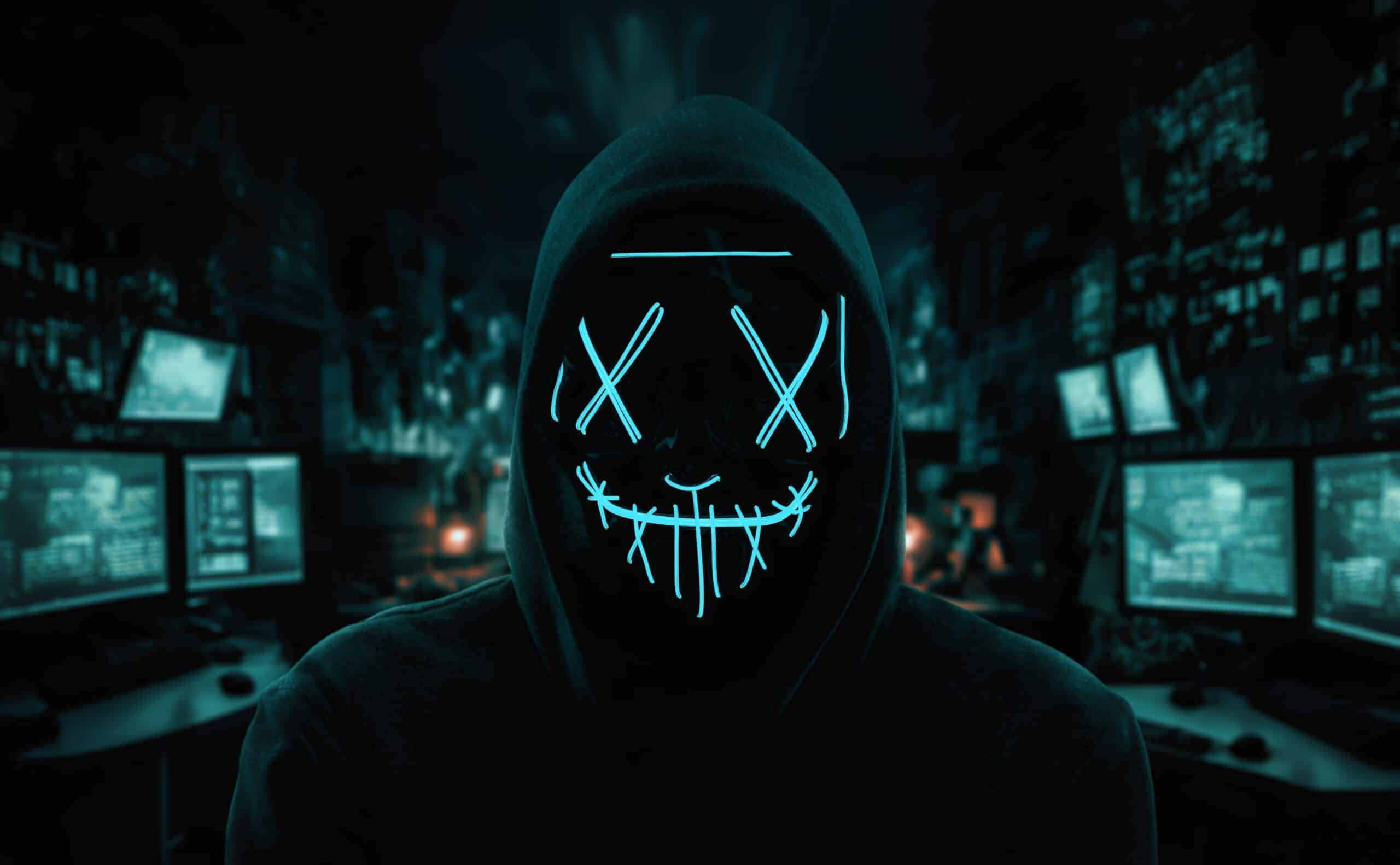 Portrait of an anonymous man, hacker wearing neon mask over dark room background (Shutterstock/Rangizzz)
