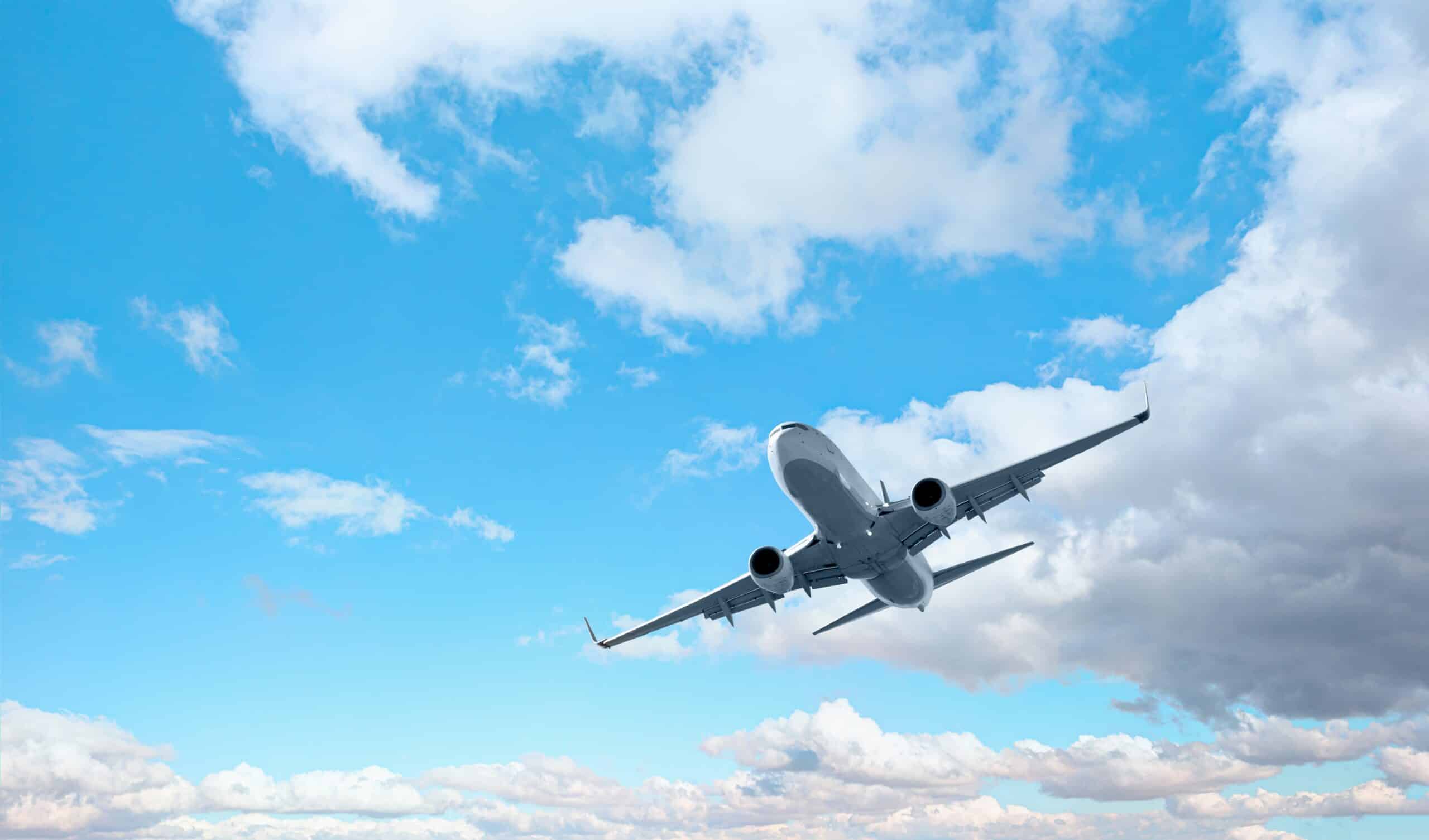 White passenger airplane flying within the sky wonderful clouds within the background - Toddle by air transport (Shutterstock)