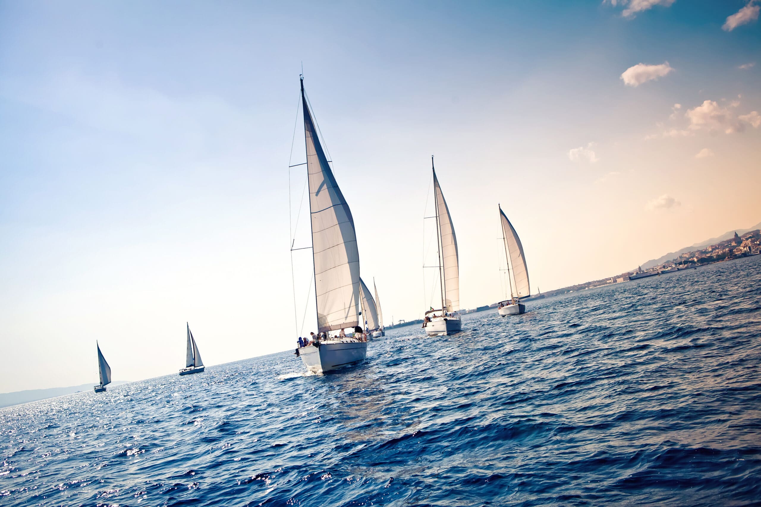 Sailing ship yachts with white sails in a row (Shutterstock)