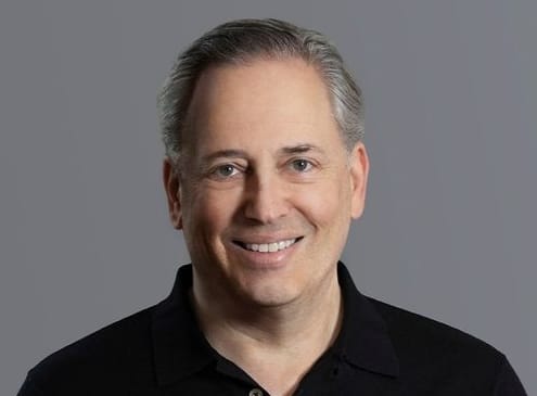 A headshot of David Sacks in a dim polo towards a gray background