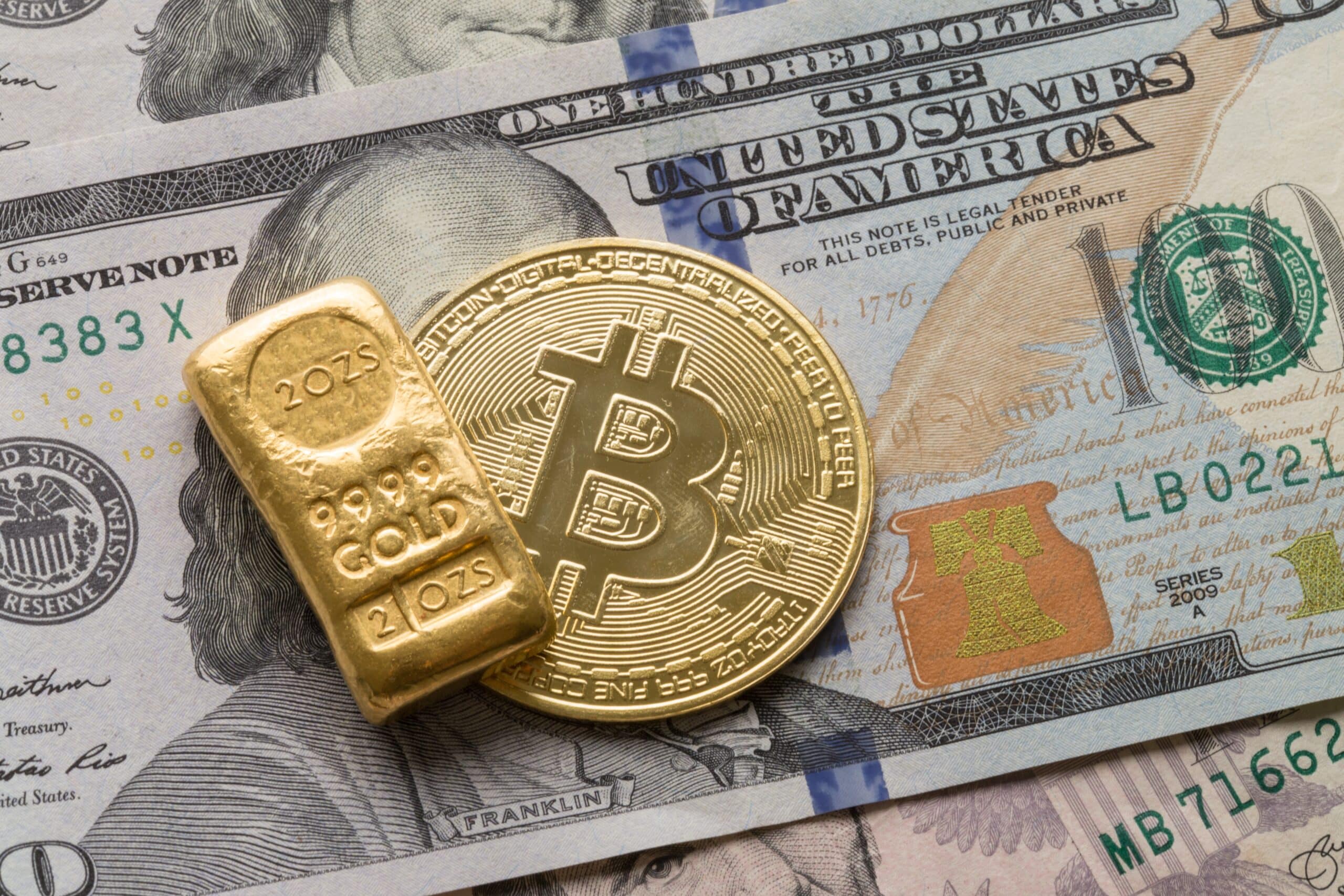 Gold Bullion and Bitcoin Cryptocurrency on 100 US Buck (Shutterstock)